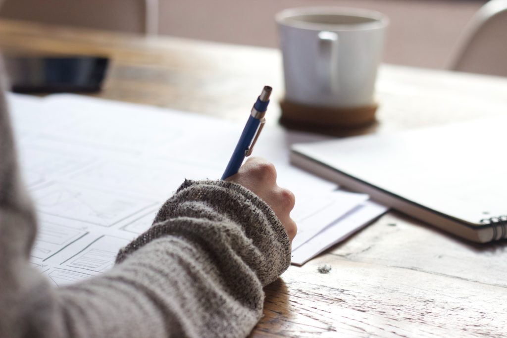 Person taking an exam on a wooden desk