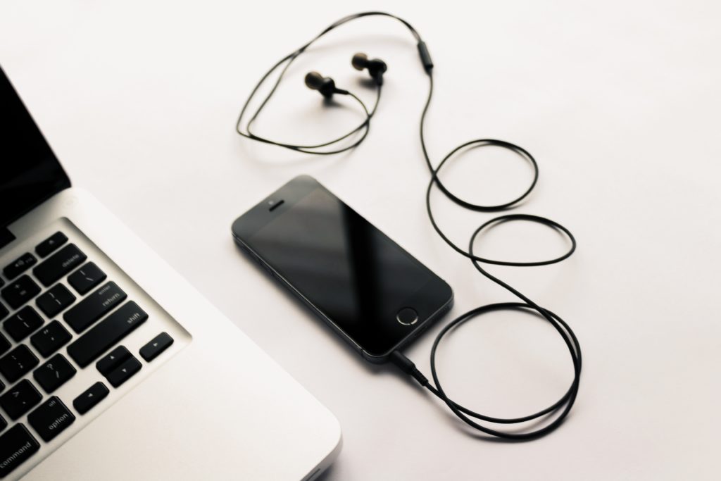 laptop and phone with earbuds connected.
