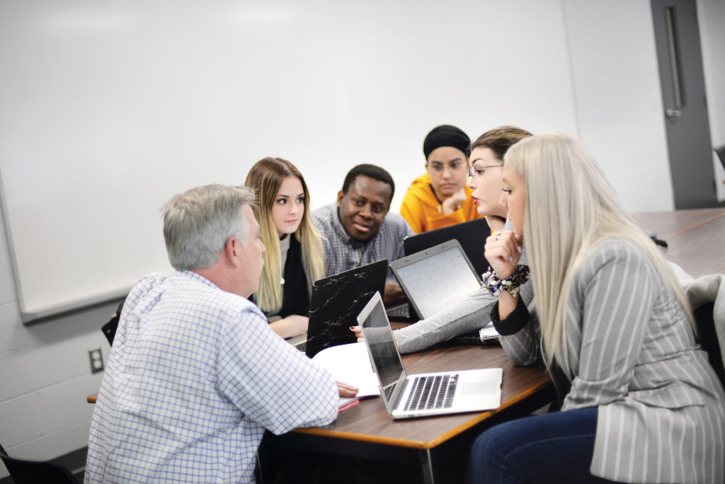 Human Resources students discussing details of a project with a faculty member.