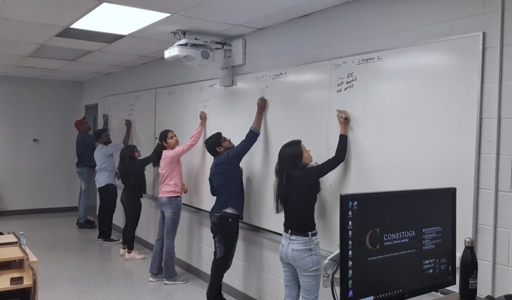 Students writing on a whiteboard.