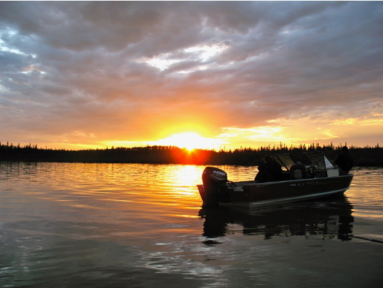 A sunset behind a lake with a motor boat