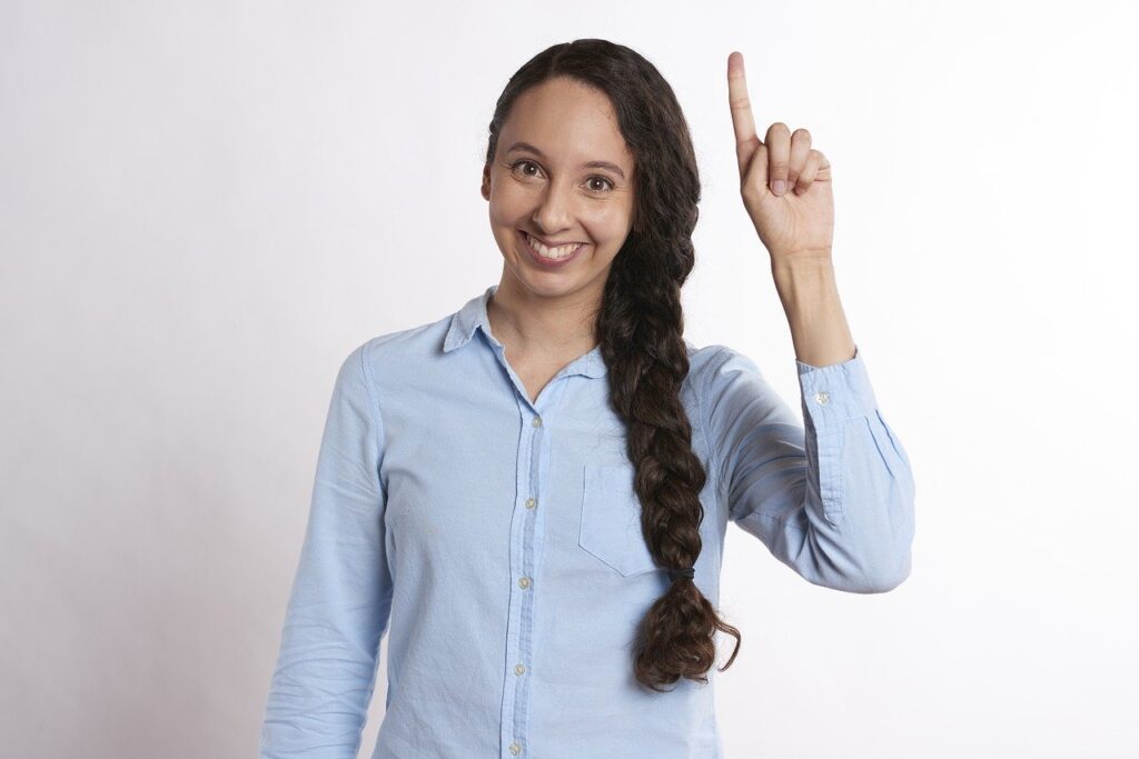 A women raising her left hand finger with a bright smile on face.