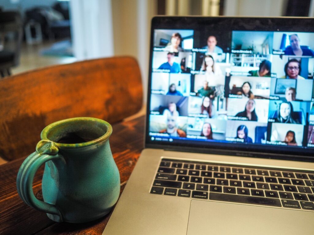 A laptop displaying a video chat screen with a coffee mug nearby.