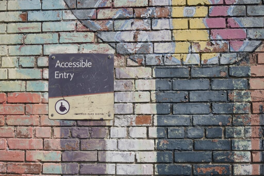 A sign, that reads accessible entry, against a brick wall