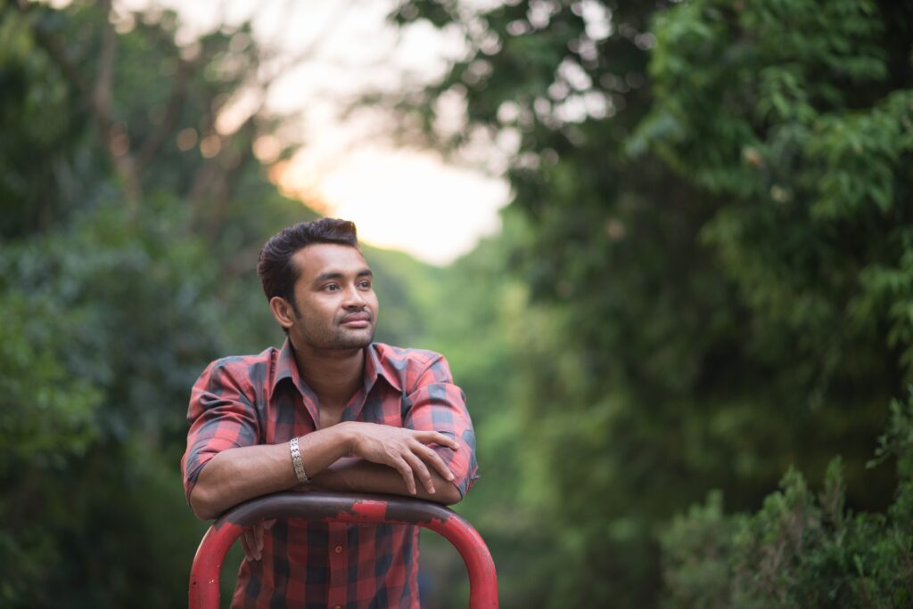 man sitting on a red chair with trees in the background