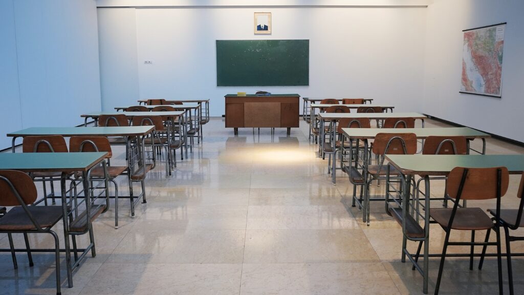 An empty classroom with a chalkboard and desk at the front