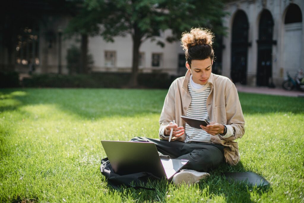 person studying with computer on grass
