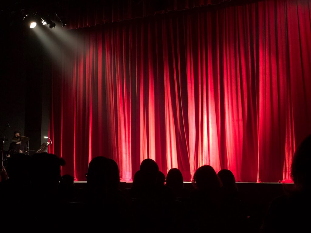 Red curtain with a silhouette of an audience and a spotlight