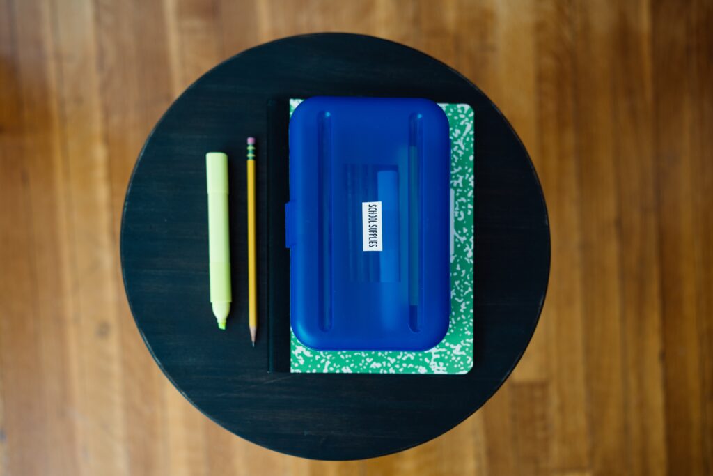 black table with blue pencil box and a pencil and highlighter