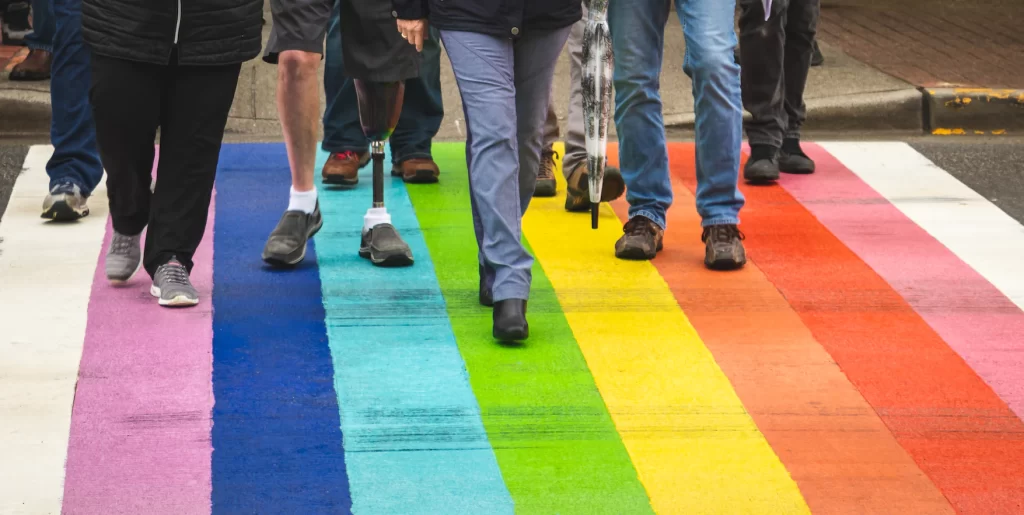 Diverse identities walking on a rainbow crosswalk