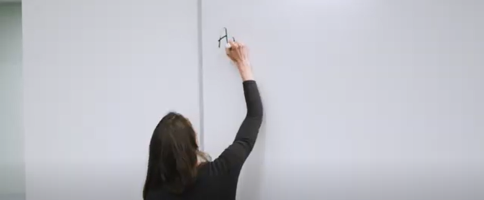 A professor is writing on the whiteboard in a college classroom