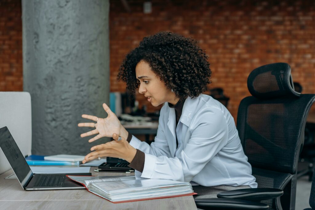 A Frustrated Woman Sitting on a Swivel Chair while Looking at the Screen of a Laptop